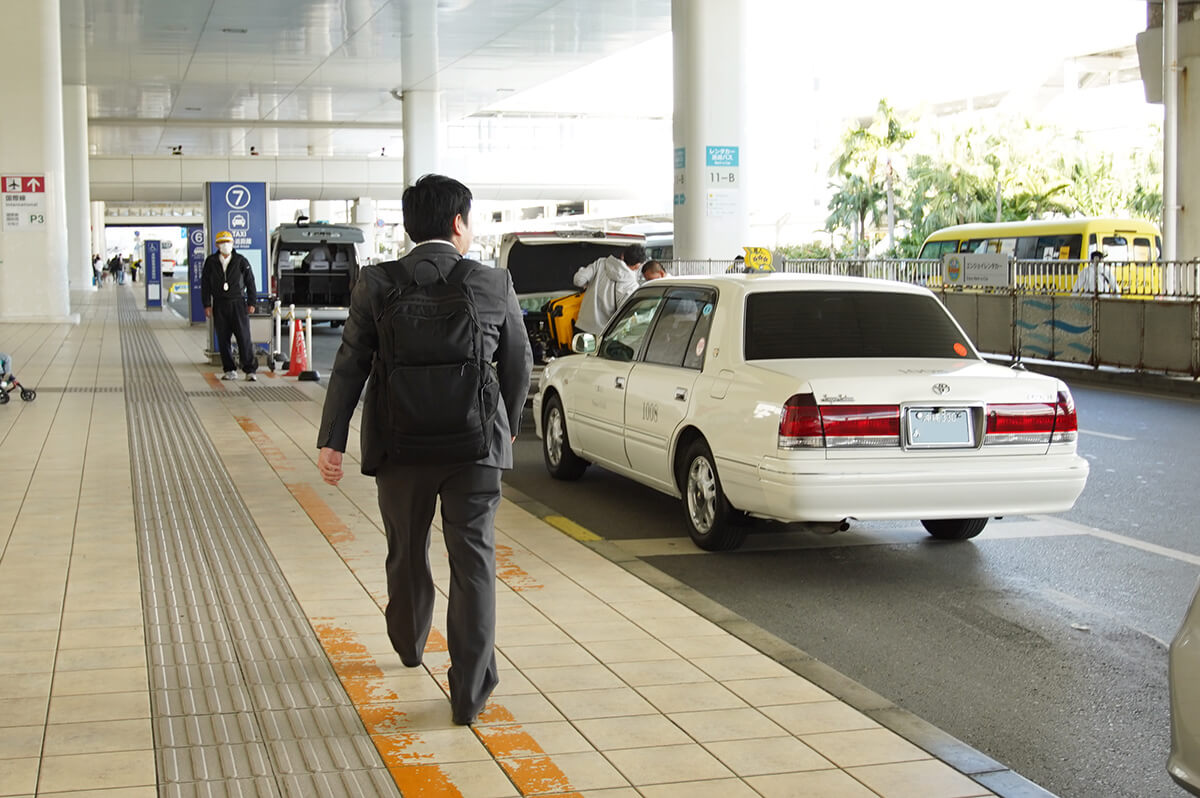 那覇空港にてタクシーを探すスーツ姿の男性